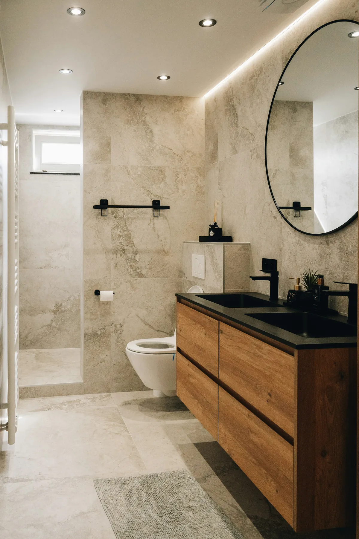 Badezimmer mit Dusche, rundem Spiegel und Holzwaschtisch